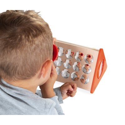 Criança a olhar para quadro de espelhos redondos num suporte de madeira com laterais laranjas