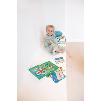 Menina loira a jogar com jogos de tabuleiro infantis coloridos numa cadeira branca