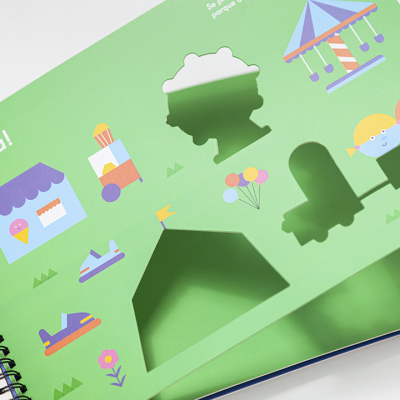 Livro infantil verde com desenhos coloridos e recortes de formas variadas, texto 'Festa!'