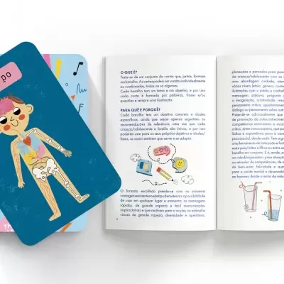Cartões educativos e livro aberto com ilustrações e texto em português sobre corpo humano e conceitos científicos.