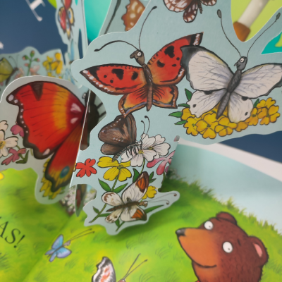 Livro pop-up com borboletas e urso em ilustração colorida
