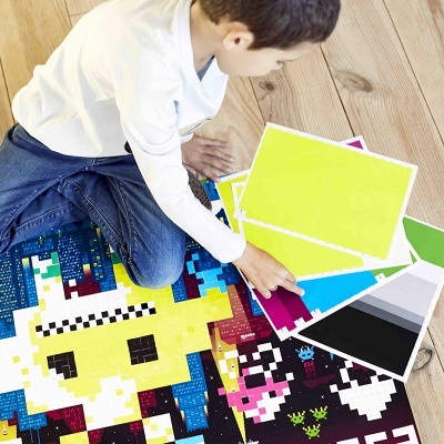 Criança a montar puzzle colorido e segurando cartas com amostras de cores