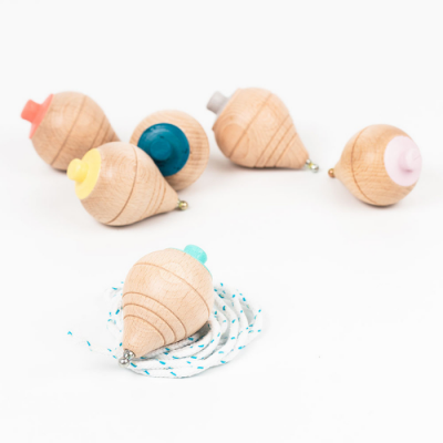 Piões de madeira naturais com topos coloridos e um com corda enrolada, sobre fundo branco