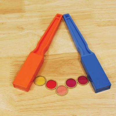 Dois ímanes azul e laranja sobre madeira clara com cinco círculos coloridos entre eles