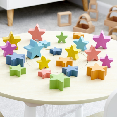 Blocos de madeira coloridos em forma de estrelas sobre mesa redonda clara