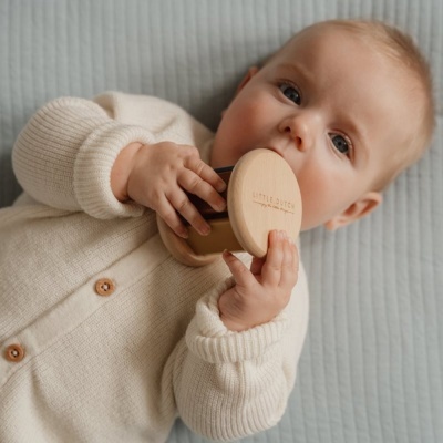 Bebé com casaco creme segurando brinquedo de madeira com texto LITTLE DUTCH
