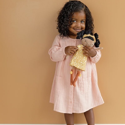 Menina com vestido rosa claro segurando boneca de pano amarela