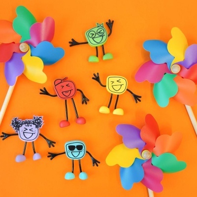 Ímanes coloridos com expressões divertidas e cataventos coloridos sobre fundo laranja