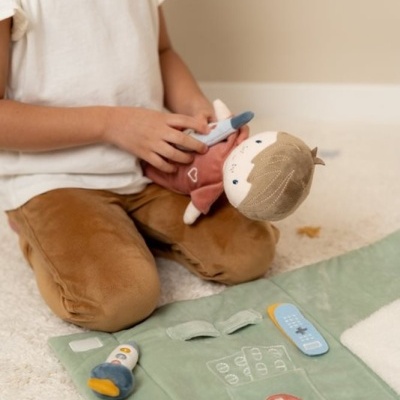 Criança a brincar com boneca e kit médico de tecido no chão