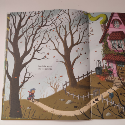 Ilustração de livro com menino de bicicleta junto a casa cor de rosa e árvores sem folhas no outono