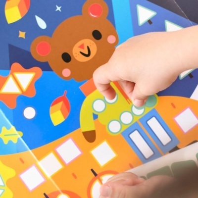Livro ou cartão com ilustração de urso castanho e mãos de criança