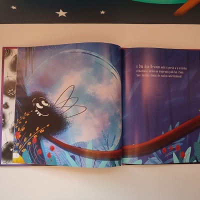 Livro infantil com ilustração de figura felpuda negra e texto em português