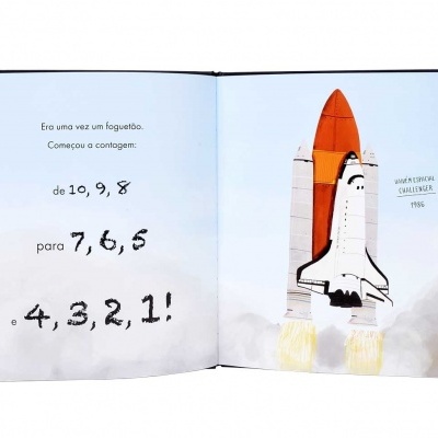 Livro infantil aberto com ilustração de foguetão e texto em português