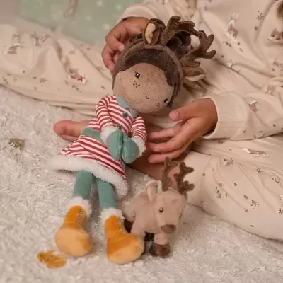 Boneca de pelúcia com vestido riscado e chifres de alce, e pequena figura de alce, nas mãos de criança com pijama estampado