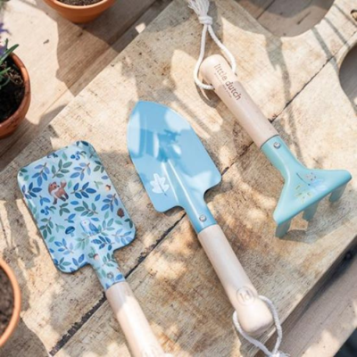 Três ferramentas de jardinagem azuis com cabos de madeira e padrões florais sobre madeira