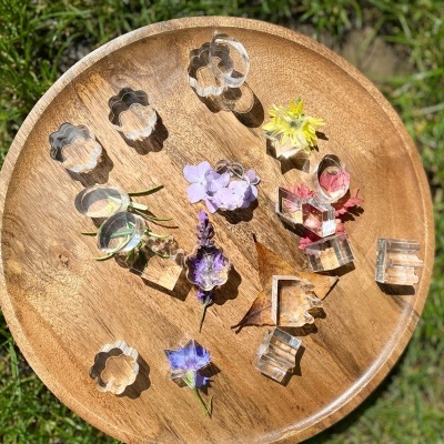 Moldes de silicone transparentes em forma de flores e letras numa bandeja de madeira com flores coloridas