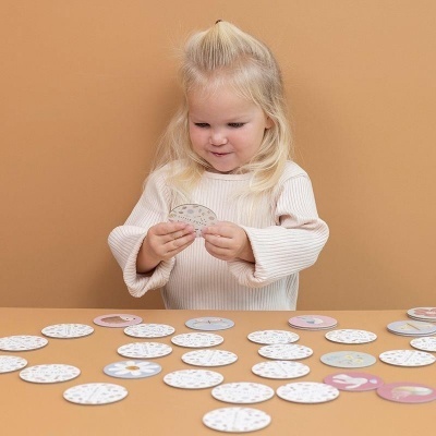 Menina a jogar com discos redondos de cartão estampados numa mesa azul