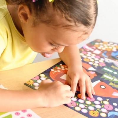 Criança a colorir livro de atividades com desenhos de animais e flores