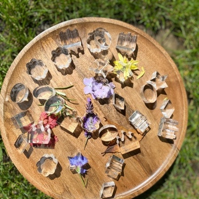 Cortadores de bolachas metálicos com flores em prato de madeira sobre relva