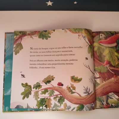 Página de livro infantil com texto em português e ilustrações coloridas de árvore, folhas e joaninha