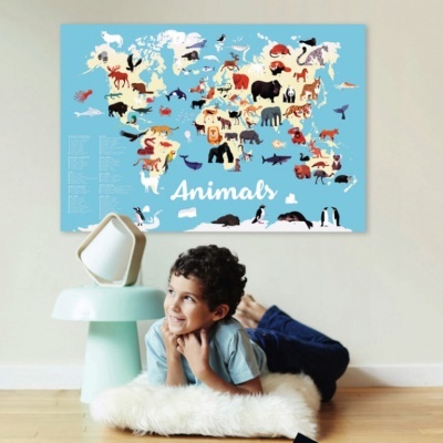 Poster do mapa-múndi com animais sob fundo azul acima de menino deitado num tapete branco
