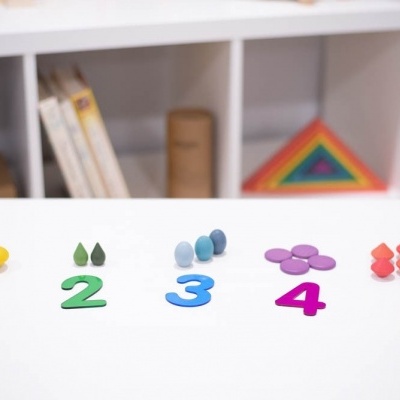 Números plásticos coloridos com ícones sobre mesa branca em ambiente de estante