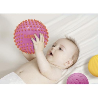 Bebé deitado segurando bola texturada rosa com relevos laranja