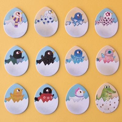 Ovos decorativos com desenhos de aves e crocodilo sobre fundo amarelo