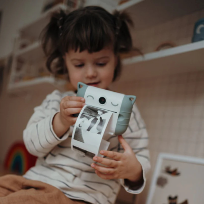 Criança com mini impressora portátil em forma de animal a imprimir fotos a preto e branco