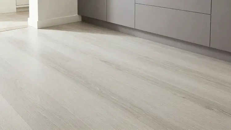 Piso em madeira clara com padrão natural e móveis cinzentos numa cozinha