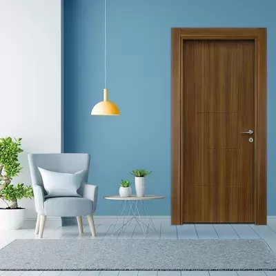 Sala with wooden brown interior door, blue wall, grey chair with cushion, yellow hanging lamp, small round table with plants, and grey rug.
