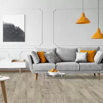 Sala de estar com sofá cinza e almofadas laranja, luminárias pendentes laranja e mesa de centro espelhada