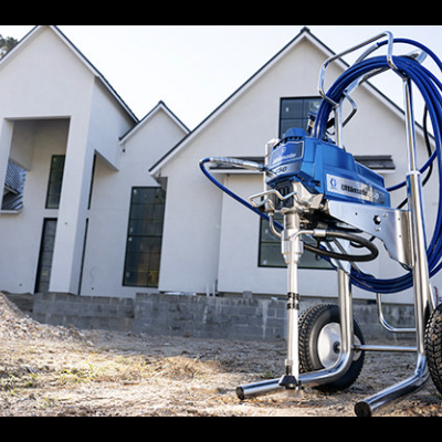 Máquina de pulverização de pintura azul e prata com rodas junto a casa em construção