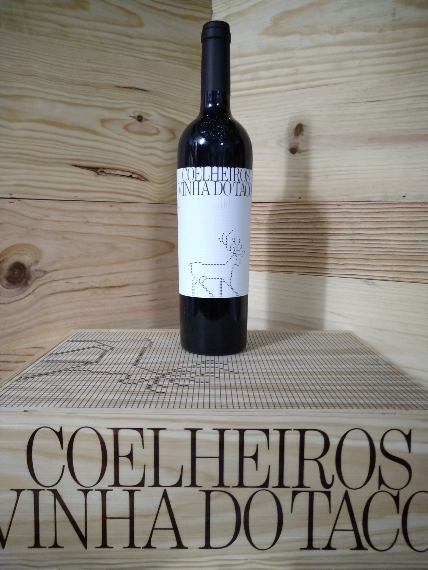 Coelheiros Vinha do Taco - 2010 Garrafa de vinho tinto Coelheiros com rótulo branco e caixa de madeira.