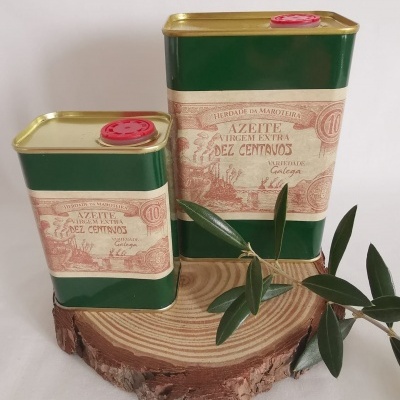 Latões de azeite virgem extra verde e dourados sobre madeira com ramos de oliveira