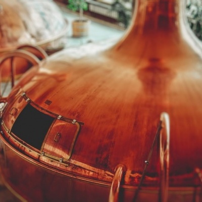 Tanque industrial de cobre com pequena porta e alças metálicas em espaço interno