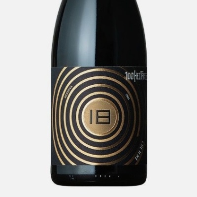 Garrafa de vinho com rótulo preto e dourado com círculos e número 18