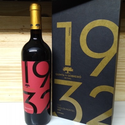 Garrafa de vinho tinto com etiqueta vermelha e preta 1932 e caixa preta com números dourados 1932