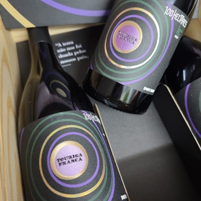 Garrafas de vinho com rótulos coloridos em caixa de madeira