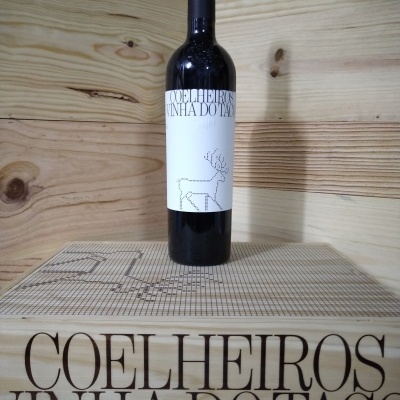 Garrafa de vinho tinto Coelheiros com rótulo branco e caixa de madeira.