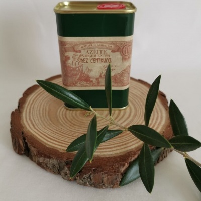 Lata verde de azeite virgem extra com tampa dourada e etiqueta antiga sobre madeira com ramos de oliveira