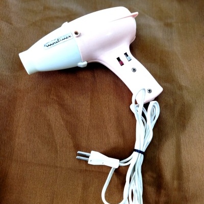 Secador de cabelo elétrico cor-de-rosa e branco com fio branco e plugue de dois pinos.