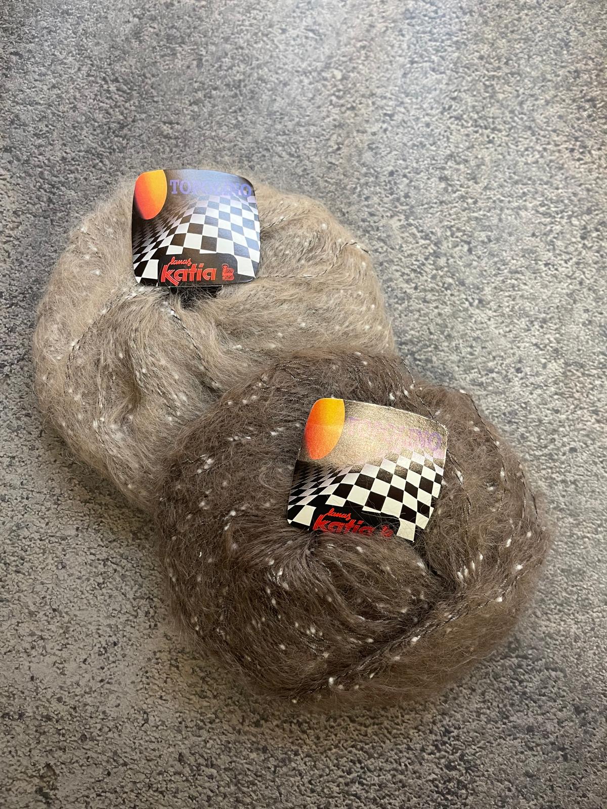 Dois novelos de lã castanha com pompons e rótulos xadrez