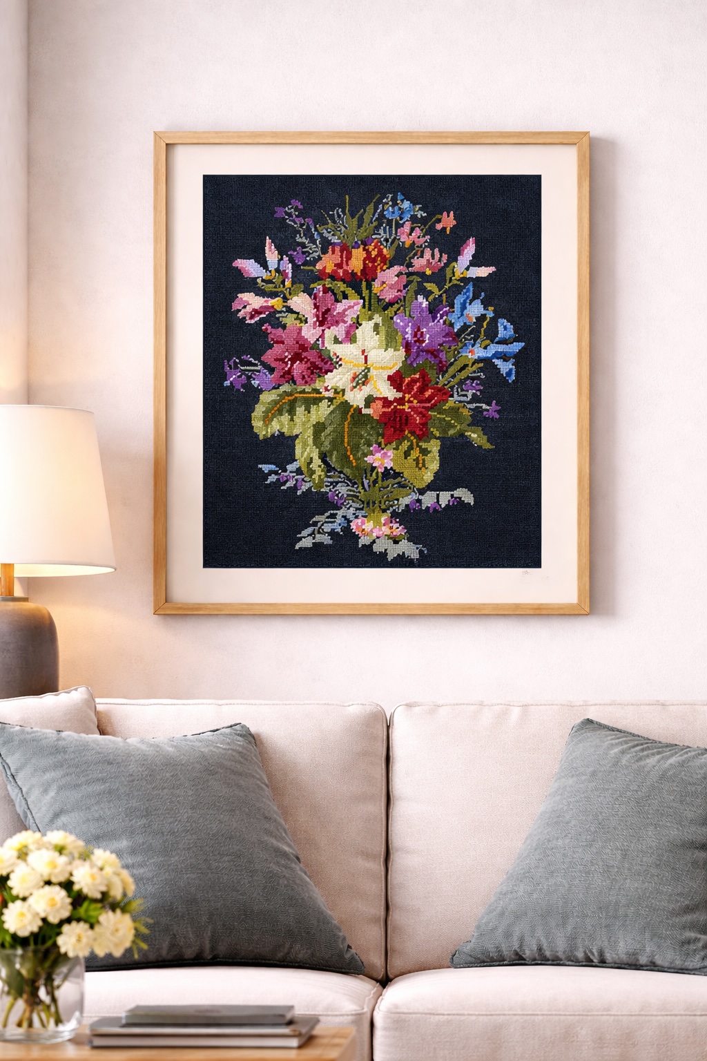 Quadro decorativo com bordado de flores coloridas em moldura de madeira sobre sofá e almofadas