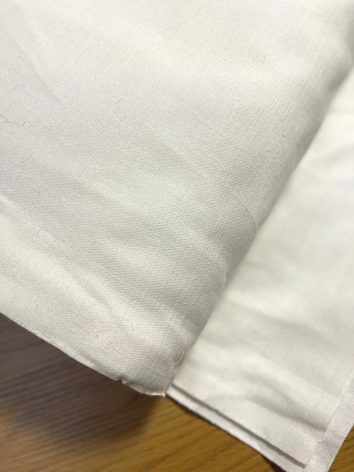 Lençol branco de algodão dobrado sobre madeira