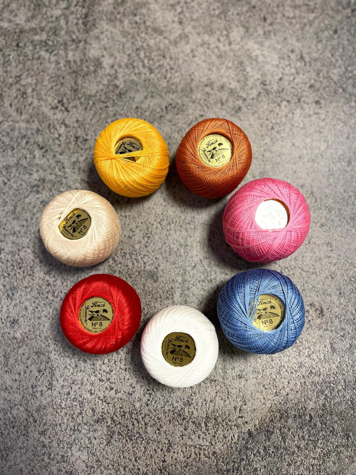 Sete novelos de linha colorida com rótulos Finca Nº 8 sobre fundo cinza