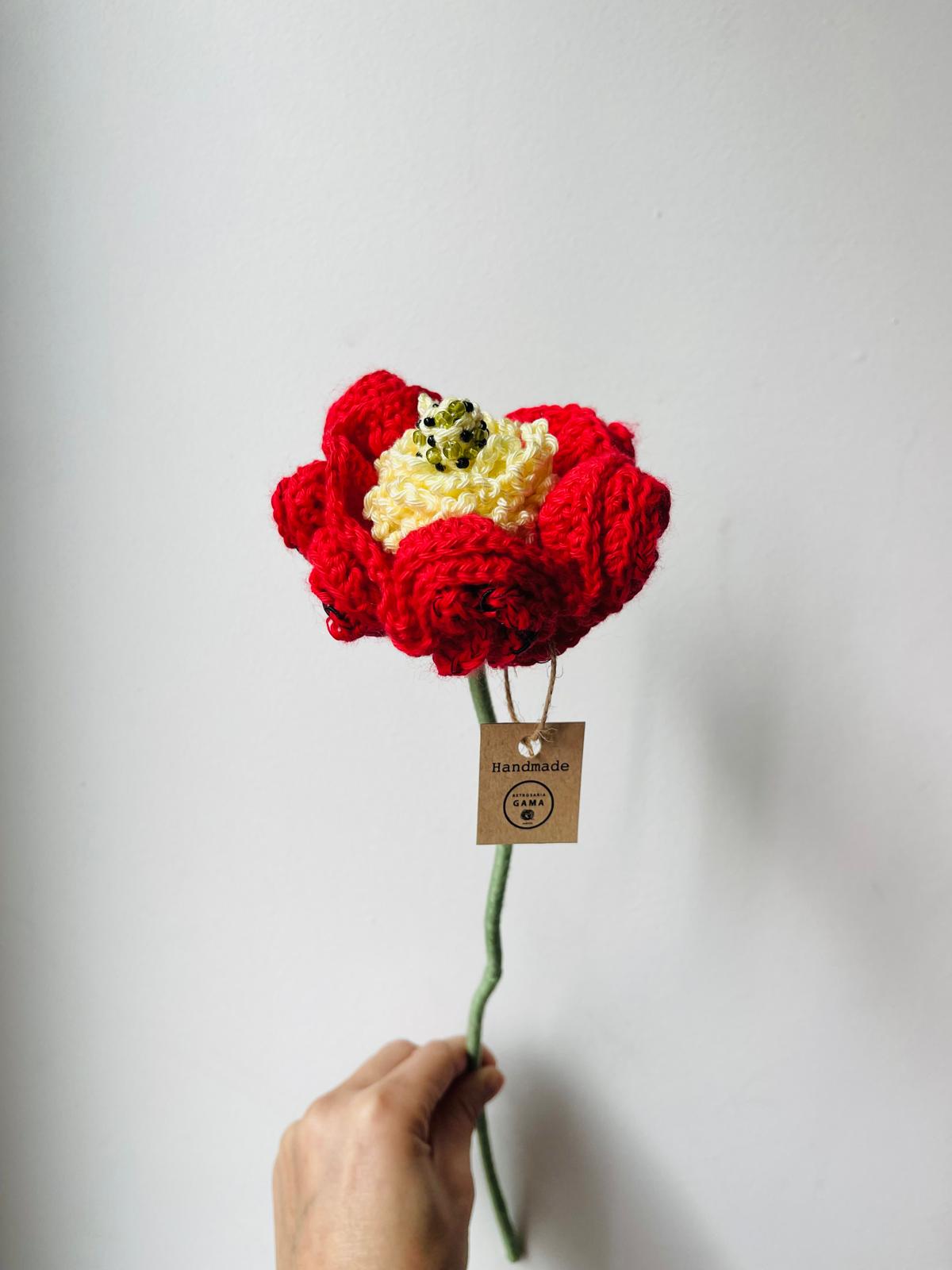 Flor feita à mão em croché a ser segurada por uma mão