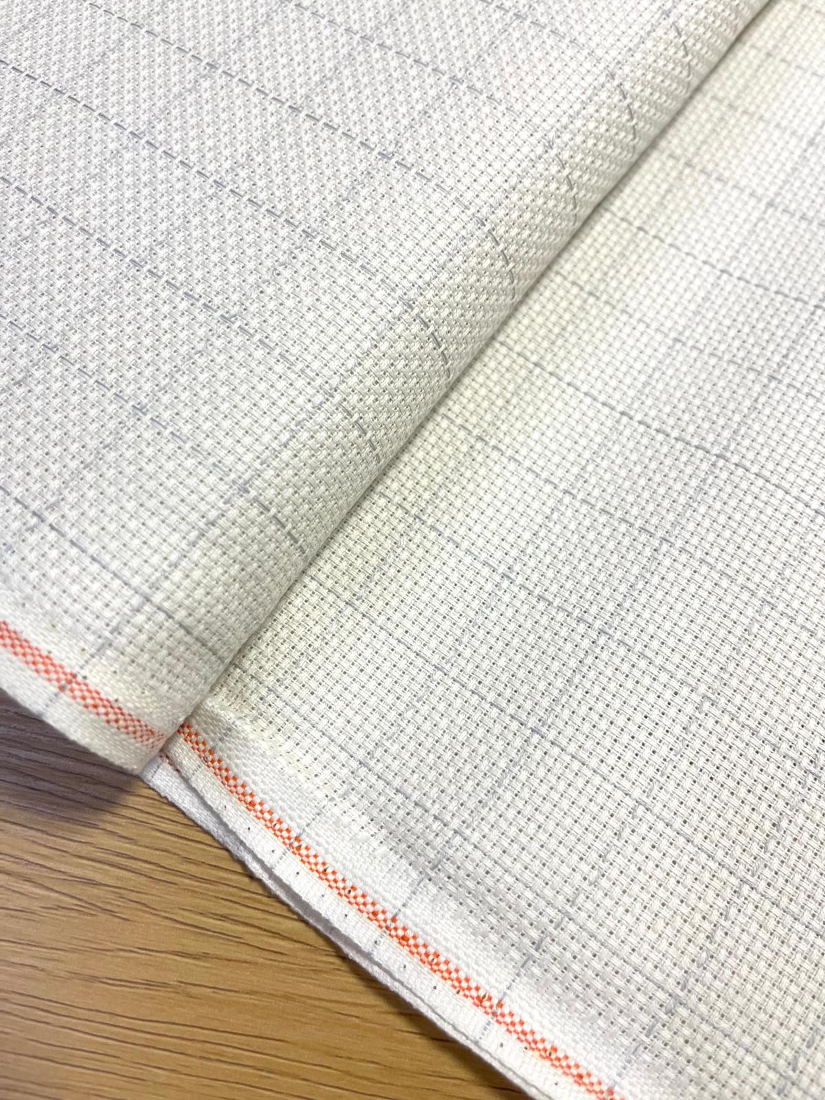 Tecido branco quadriculado com detalhes laranja numa superfície de madeira