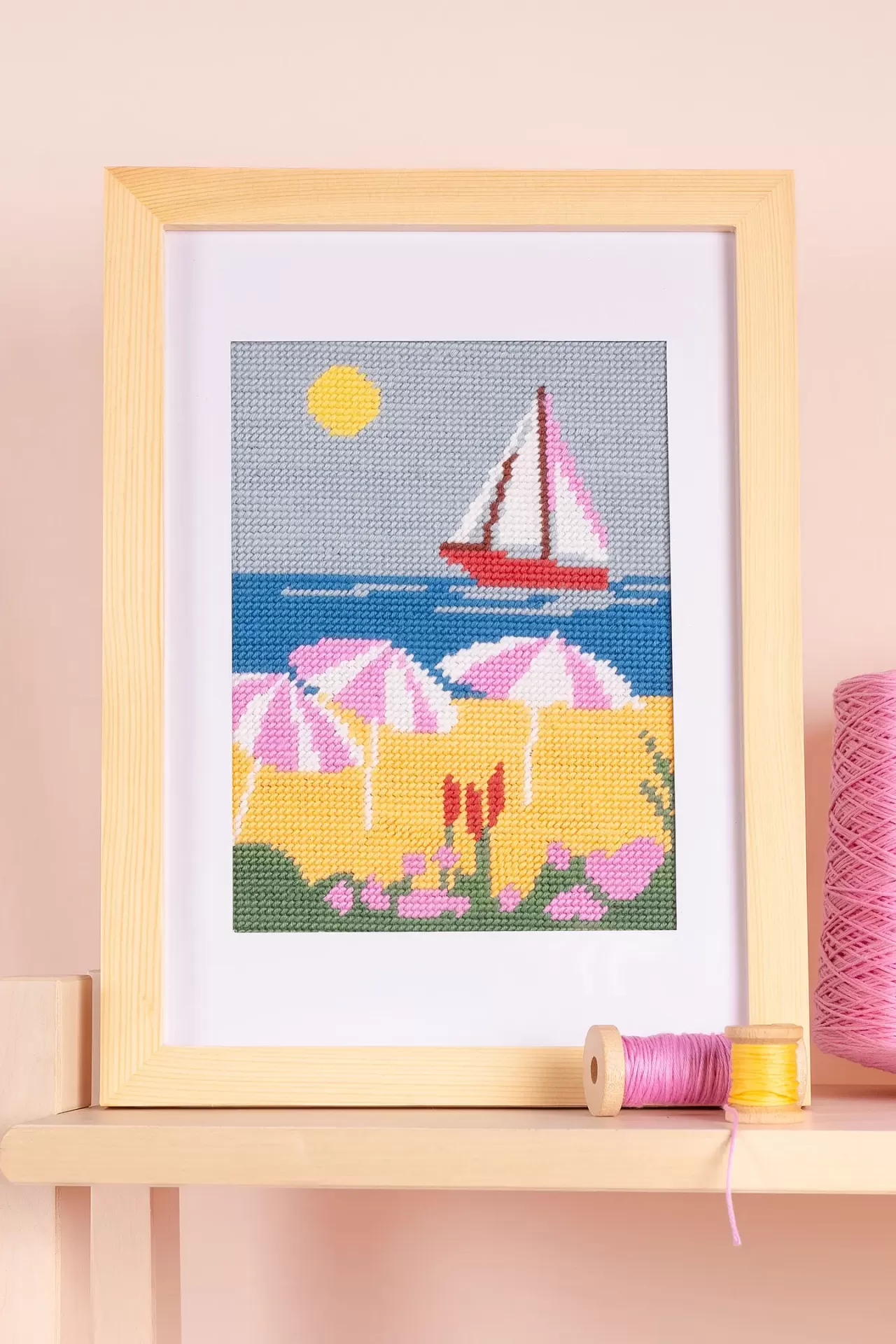 Quadro de bordado com paisagem de praia e barco