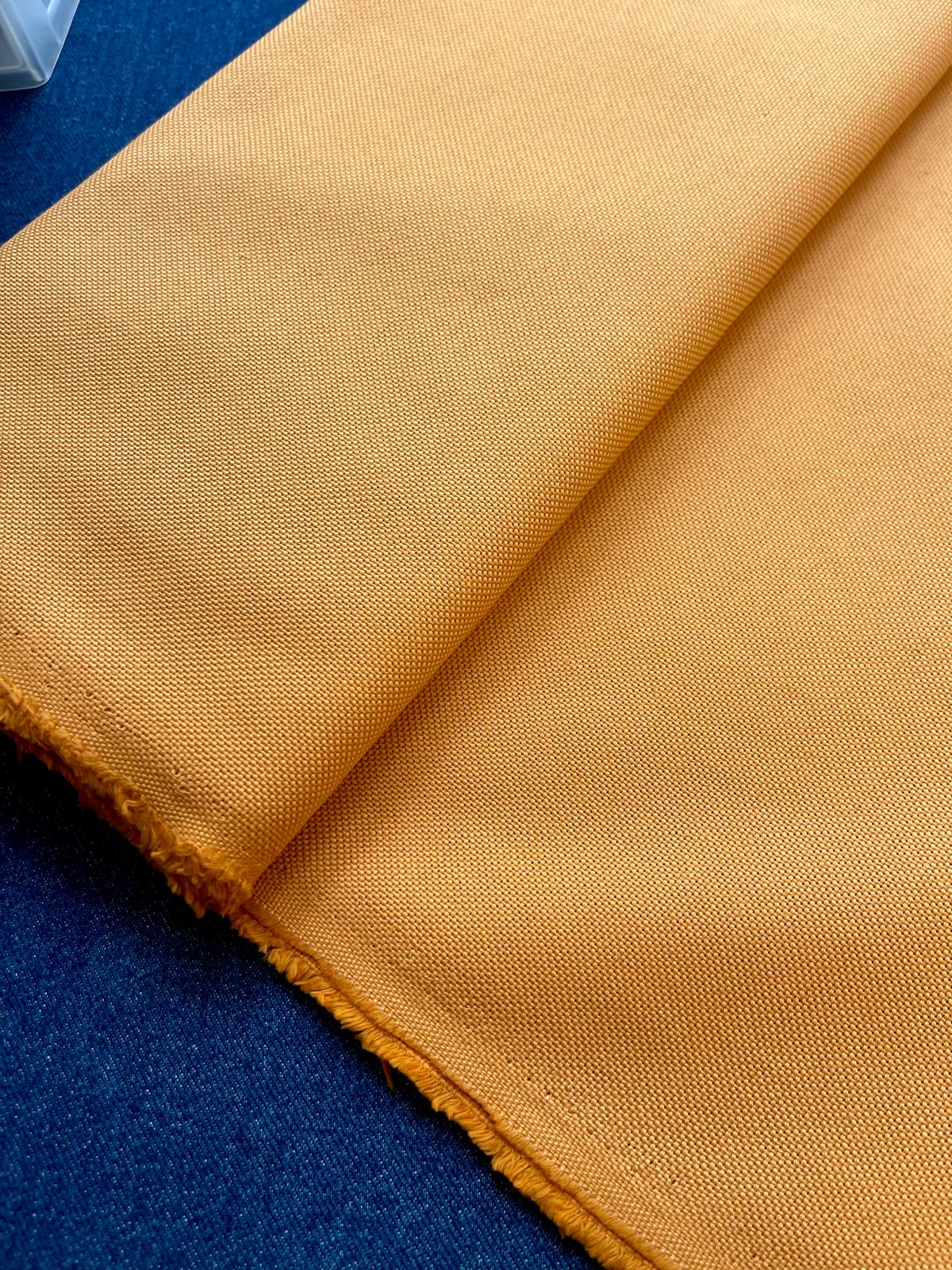 Tecido amarelo mostarda com textura densa sobre superfície azul escura